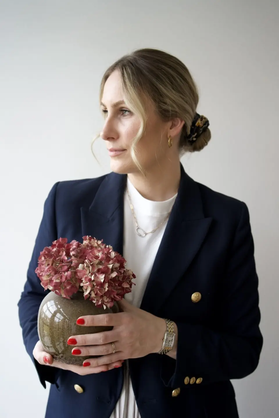 Nora-Aileen Koch, Gründerin und Creative Director von Studio Olivia Interior, im dunkelblauen Blazer mit einer Keramikvase und getrockneten Hortensien