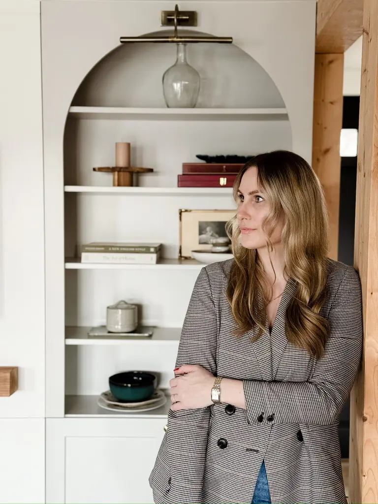 Nora-Aileen Koch, Gründerin von Studio Olivia Interior, vor einer weißen Bogennische mit gestylten Regalböden